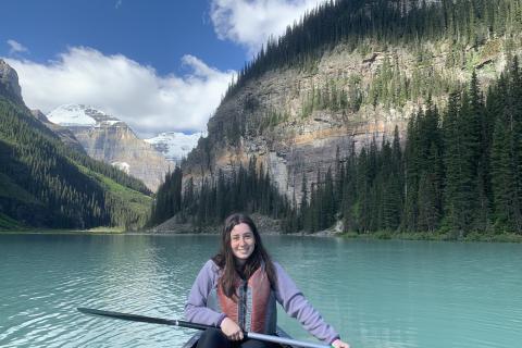 Woman in canoe in a lake in front of mountains