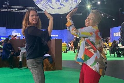 two delegates pretend to hold up a globe