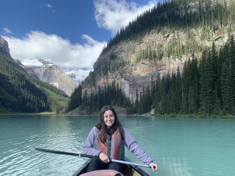 Woman in canoe in a lake in front of mountains