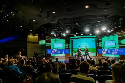 Two speakers on stage in front of large audience