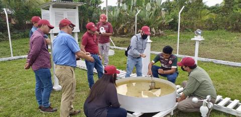 9 individuals working around a small white, metal pool of water