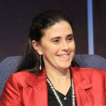 Anne-Hélène's headshot. She is wearing a red jacket and sitting in a chair