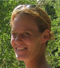 Gabriela's headshot. She wearing sunglasses on her head with her hair pulled back and is in front of leafy green trees. 